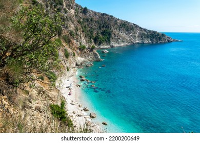 Small pebble Filikuri beach surrounded by steep high cliffs, which can only be reached from the sea. Ionian sea. Albania. Top view. Summer sunny blue landscape.