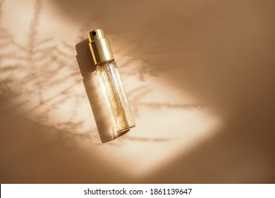 Small Perfume Bottle On Warm Pastel And Golden Colors Table. Commercial, Brand Packaging Mockup. Copy Space. Refillable Travel Size. Product Photography