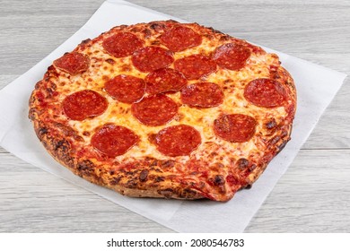 A Small Personal Size Pepperoni Pizza On Plain Waxed Paper