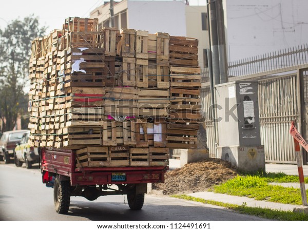 A small\
Peruvian truck overloaded with\
pallets.