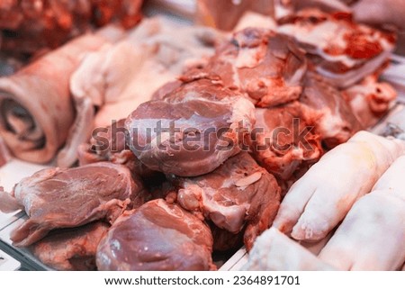 Small pig cloven foot and pork shoulder meat for sale in plastic boxes on display in window of variety meat butchering shop