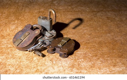 small pile of assorted old rusty padlocks and keys sat on hardboard table
