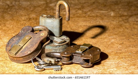 small pile of assorted old rusty padlocks and keys sat on hardboard table