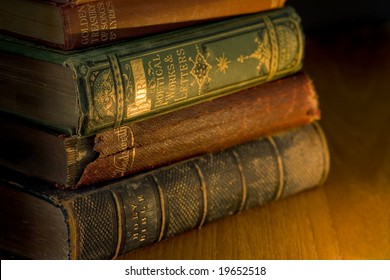 a small pile of old books lit by candle light
