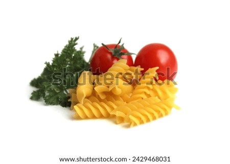 A small pile of pasta lies on a white background with tomatoes and herbs.