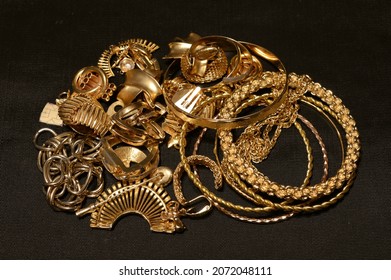 A Small Pile Of Scrap Gold Collection Over A Black Fabric Background.