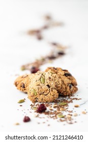 A Small Pile Of Trail Mix Cookies With A Trail Of The Mix Blurred Out In Behind.