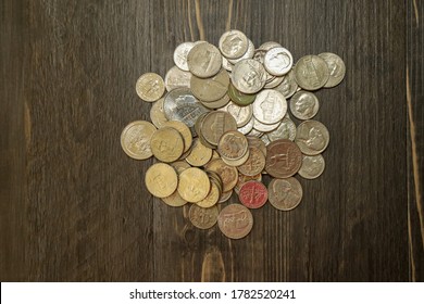 A Small Pile Of US Silver Coins On A Wooden Surface.