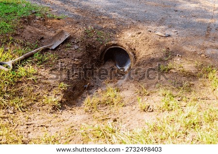 Small pipe lets water flow into cleaning drainage trench dirt path nearby, soil