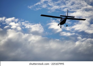 Small Plane In The Air. Blue Sky With White Clouds.