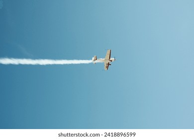  A small plane in a blue sky with a contrail. High quality photo