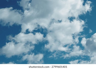 A small plane soaring through a bright blue sky with fluffy white clouds.