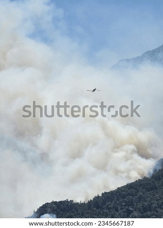 A small plane that monitors forest fires from the air. Airplane in the Sky over Clouds with Mountain Background.