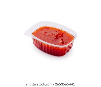 A small plastic container filled with a vibrant red, tangy dipping sauce sits on a plain background, perfect for enhancing the flavor of various dishes during meals or snacks.