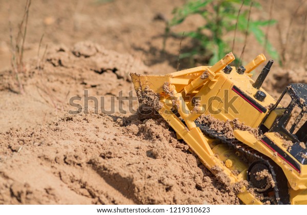small plastic toy digger working on sand quarry,\
construction concept
