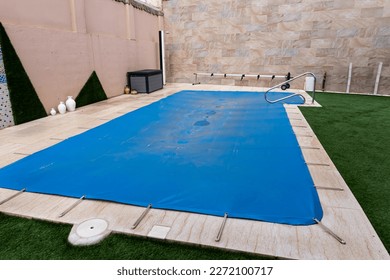 Small pool covered with a blue tarpaulin during the winter season to cover it and prevent dirt and objects from entering the water.