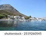 The small port of Telendos greets visitors with its charming waterfront, colorful boats, and peaceful atmosphere, offering a warm welcome to this serene Greek island.