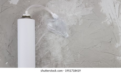 A Small Portable Oxygen Tank And A Mask On A Gray Concrete Background