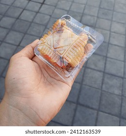 The small portion of fried food that is famous in Indonesian people. It is hold by the hand and the food is wrapped by the square tiny plastic box.