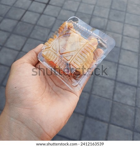 The small portion of fried food that is famous in Indonesian people. It is hold by the hand and the food is wrapped by the square tiny plastic box.