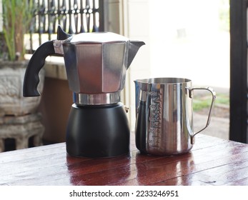 Small pressure coffee pot, Moka Pot, made of aluminum material, placed on a dark wooden floor table.  Ready to solve the stainless steel measure  The photo presents a shallow depth of field. - Shutterstock ID 2233246951