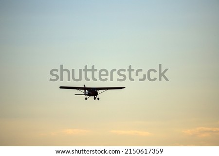 Small private red propeller plane flies in the sky
