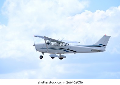 A Small Private Single Engine Airplane Is In Flight With Fluffy Clouds In The Background