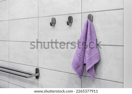 A small purple towel hangs on a metal hook