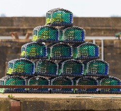 Small Pyramid Shape Made Up Of Fifteen Multi Colored Lobster, Crab Pots (traps), On A Quay Side.
