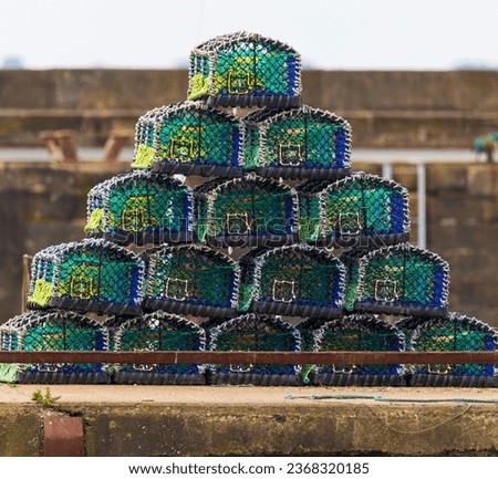 Small pyramid shape made up of fifteen multi colored lobster, crab pots (traps), on a quay side.