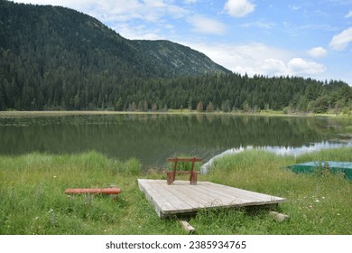 Small raft with bench on Zminicko jezero lake in Durmitor National Park in Montenegro, with mountains in the background under blue sky in summer - Powered by Shutterstock