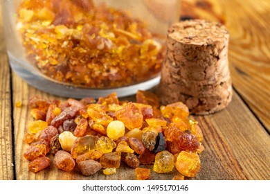 Small Raw Amber In A Glass Bottle On A Wooden Table. A Precious Find From The Coast Of Central Europe. Light Background.