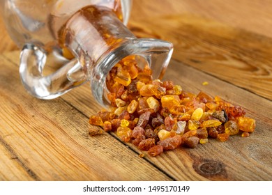 Small Raw Amber In A Glass Bottle On A Wooden Table. A Precious Find From The Coast Of Central Europe. Light Background.