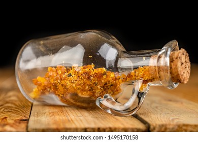 Small Raw Amber In A Glass Bottle On A Wooden Table. A Precious Find From The Coast Of Central Europe. Dark Background.