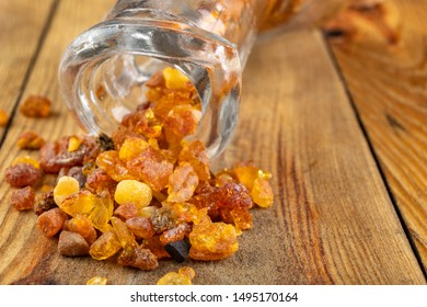 Small Raw Amber In A Glass Bottle On A Wooden Table. A Precious Find From The Coast Of Central Europe. Light Background.