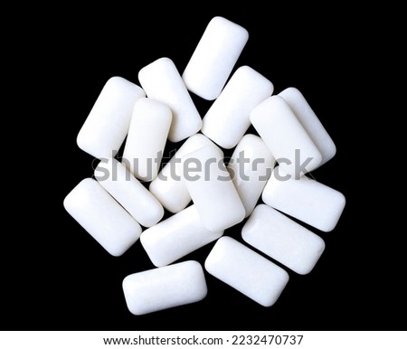 Small rectangular white chewing gums, heap, black background