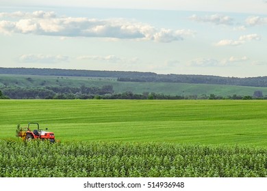 Small red farm tractor on a background of green meadows. Agricultural background with copy space. - Shutterstock ID 514936948