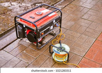 A Small Red Generator On The Street On An Orange Wire Gives Electricity