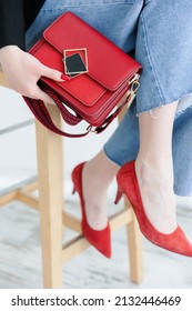 Small Red Handbag. Fashionable Women's Leather Clutch Bag With A Fabric Strap In The Tone Of The Shoes. Girl . Traditional Clutch Bag With Brooch. Bag Made Of Fine Red Genuine Leather. Front View. 