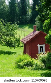 Small Red Idyllic Farmhouse/ Cottage In A Sunny Summer Green Landscape (Finland Scandinavia)