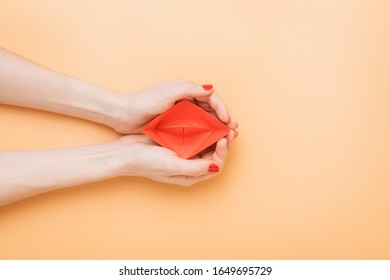 small red paper boat in female palms. conceptual abstract image of the vagina