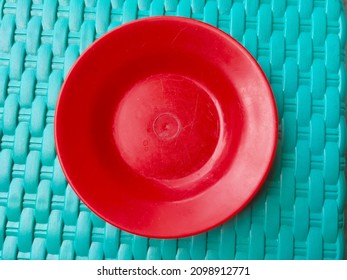 Small Red Plastic Plate On A Green Texture Background