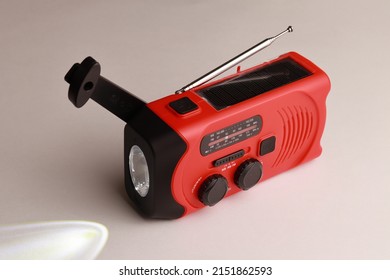 Small Red Portable Radio Rechargeable With Solar Panels Or Manually With A Crank. Flashlight Included