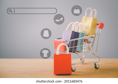 Small Red Shopping Paper Bag On Wood And Blurred  Cart, Search Bar Beside With Copy Space, Online Shopping Concept, E-commerce, Buying Or Selling Goods Or Services Online Over The Internet