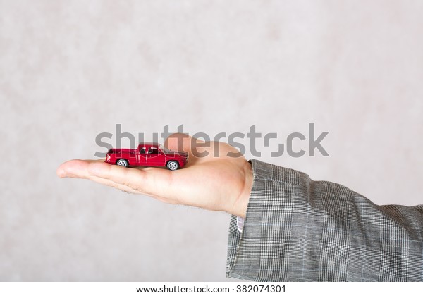 A small red toy car in the hand of a\
business man. Closeup. Free space for a\
text.