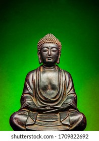 A Small Replica Statue Of The Buddha With A Green Background.  Green Symbolizing Cleanliness And Purity From Contamination.