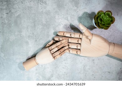 A small right wooden mannequin hand with a bigger size right wooden mannequin hand, isolated on grey marble background. - Powered by Shutterstock