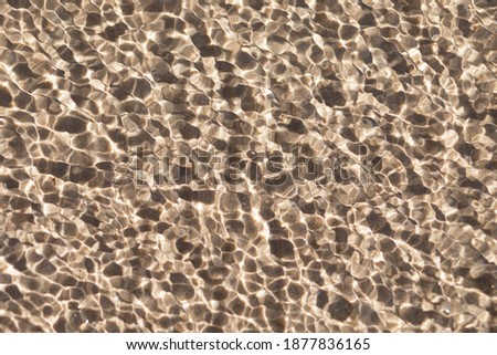 Small ripples and waves in sea on water above sand and bottom. Natural texture, background, surface with copy space.