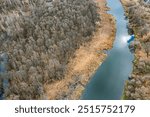 small river with coastal wetland. bare forest trees on riverbanks. aerial view from flying drone.