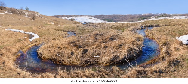 small river flow through dry spring prairie